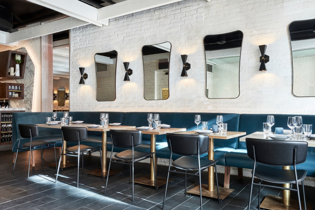 Dining area with wooden tables, teal banquette seating, and decorative wall mirrors
