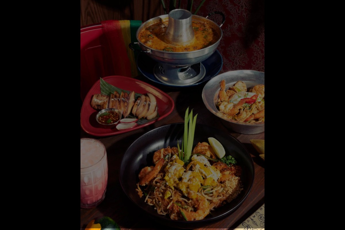 Table spread with pad thai, satay skewers, shrimp salad, and a hot pot soup
