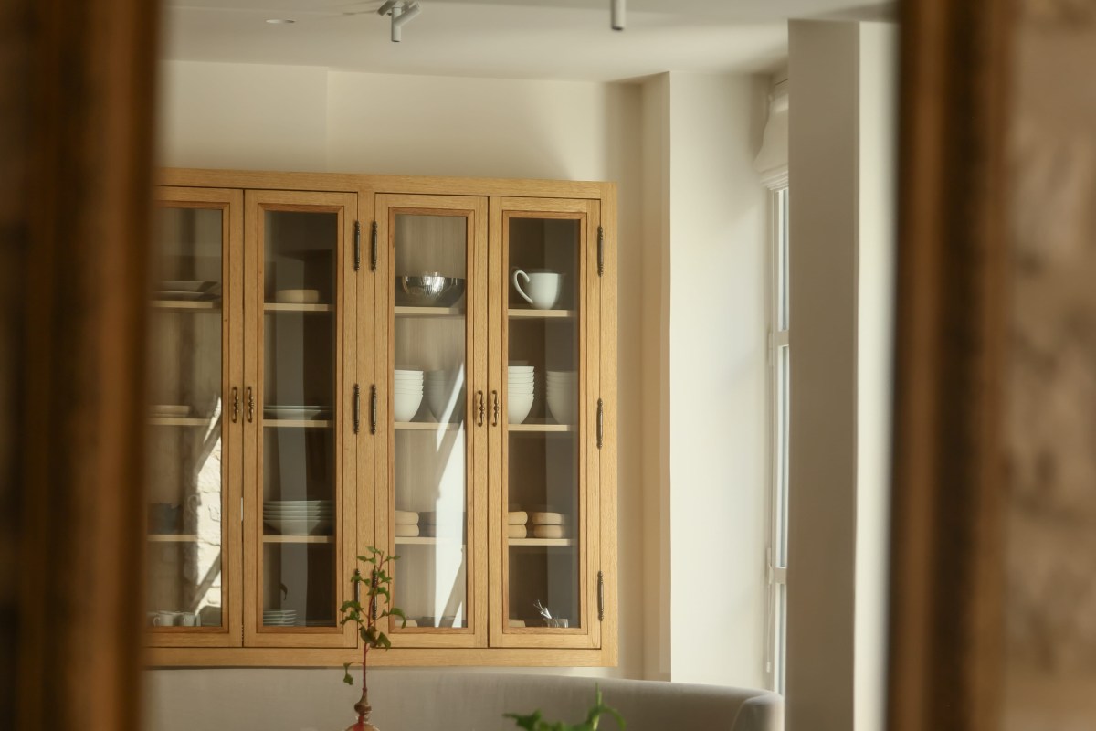 View through doorway into dining room with built-in oak glass-front cabinet displaying tableware