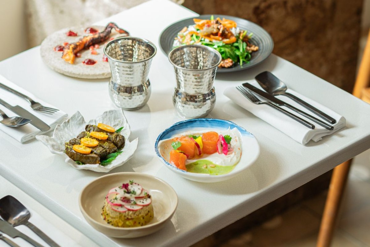 Laid table with starters, pita, hummus, and shrimp dish, silver cups and cutlery