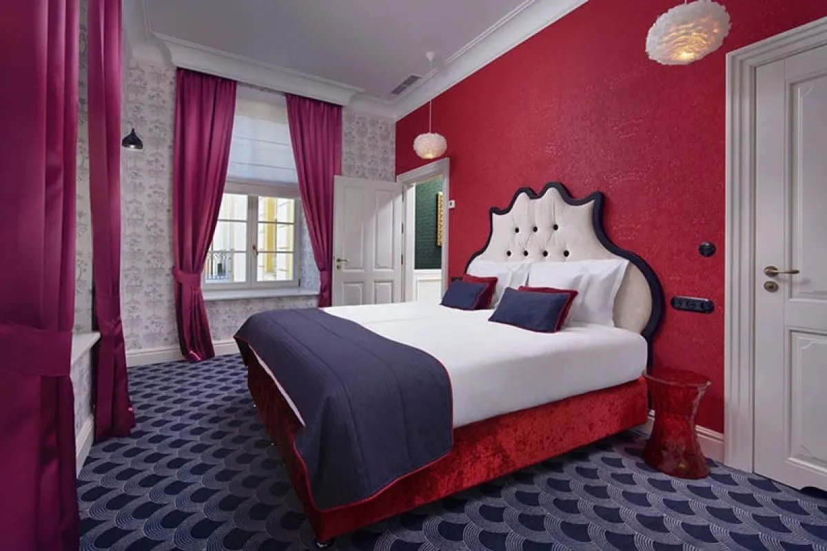 Guest room with bold red accent wall and purple curtains