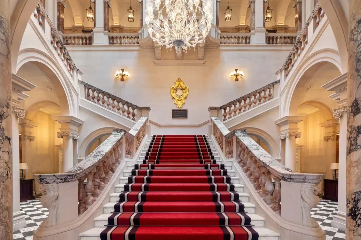 Grand marble staircase with red carpet and chandelier in hotel lobby