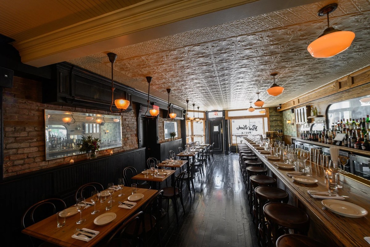 Interior dining room with tin ceiling, long wooden bar, bentwood chairs and brick walls