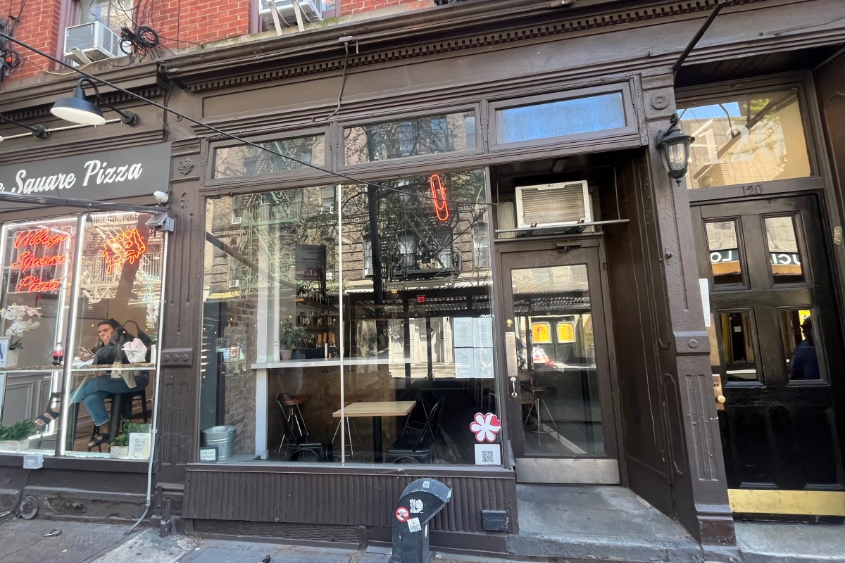 Exterior storefront of Red Paper Clip restaurant with neon paper clip sign and dining tables visible through window