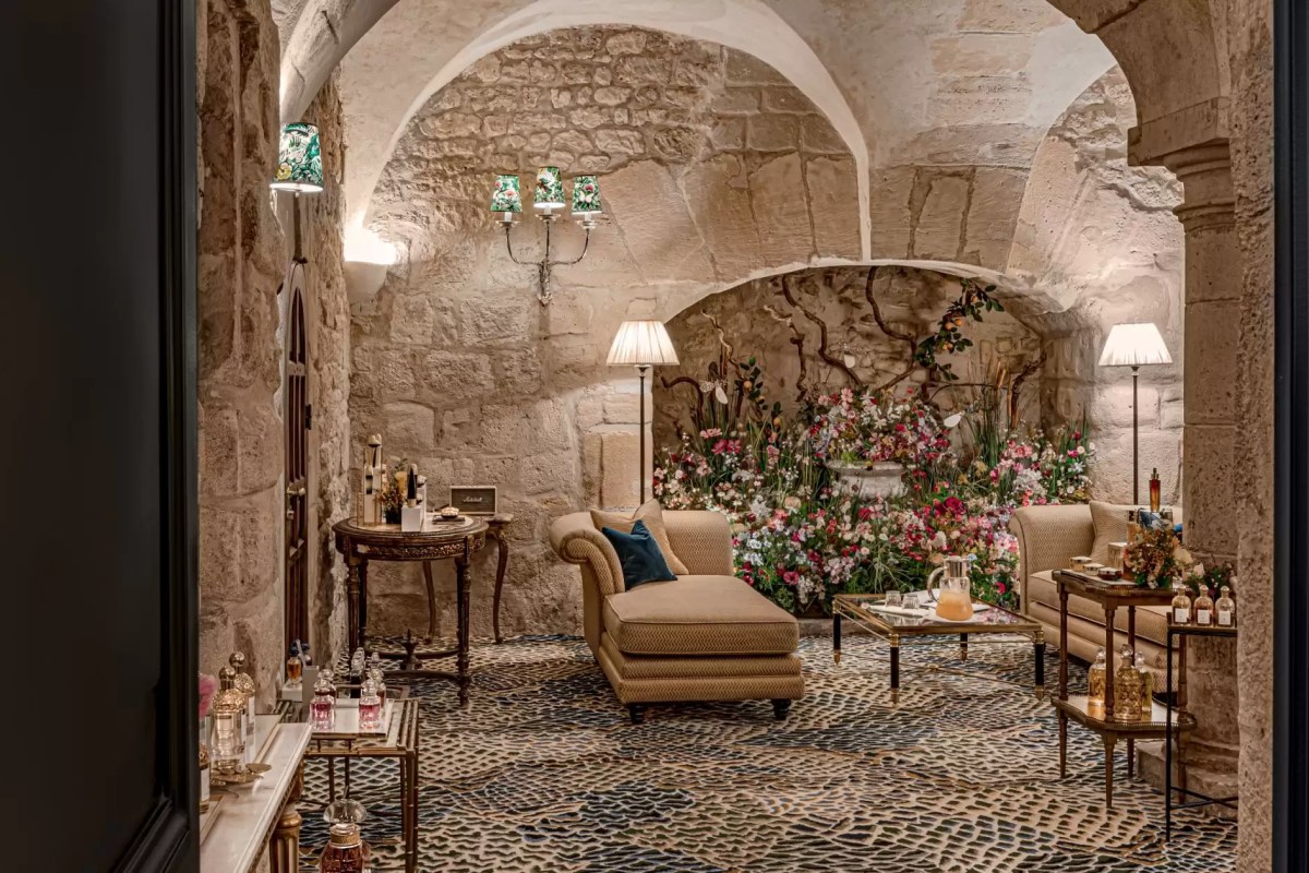Vaulted stone-walled lounge/spa area with armchairs, floral display and perfume bottles on display