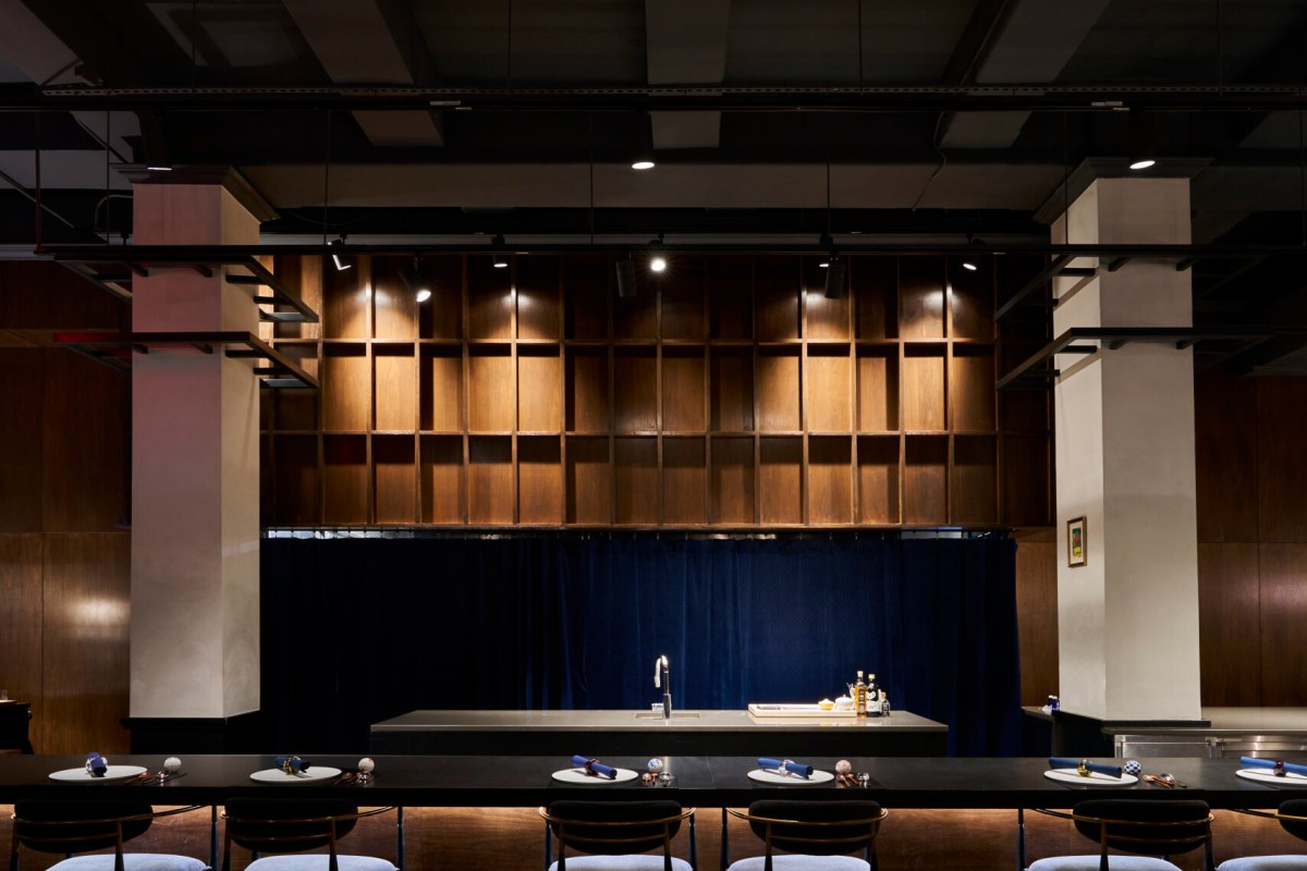 Restaurant dining counter with wood paneling, blue curtain, and place settings along a dark counter