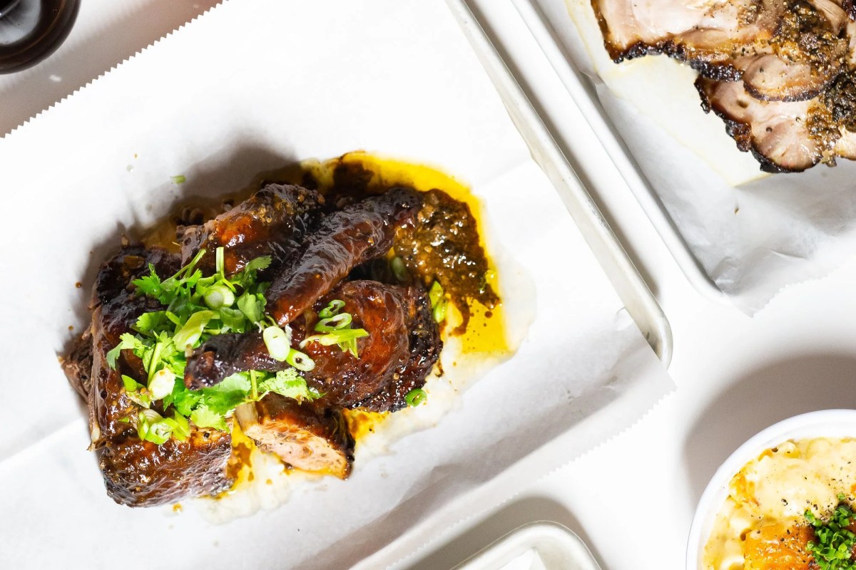 Overhead shot of glazed ribs with scallions and cilantro beside sliced pork and mac and cheese