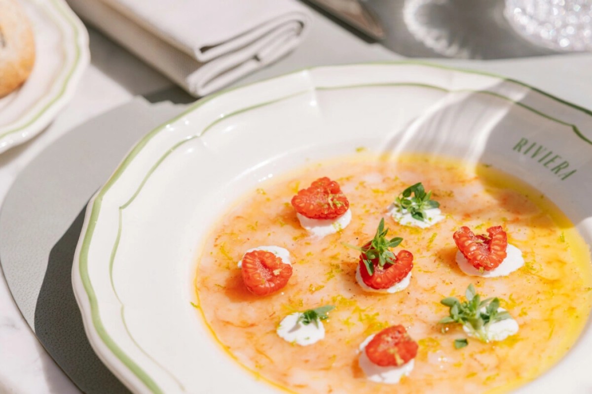 Elegant plated dish with pink sauce, raspberries and herbs on a white plate labeled Riviera