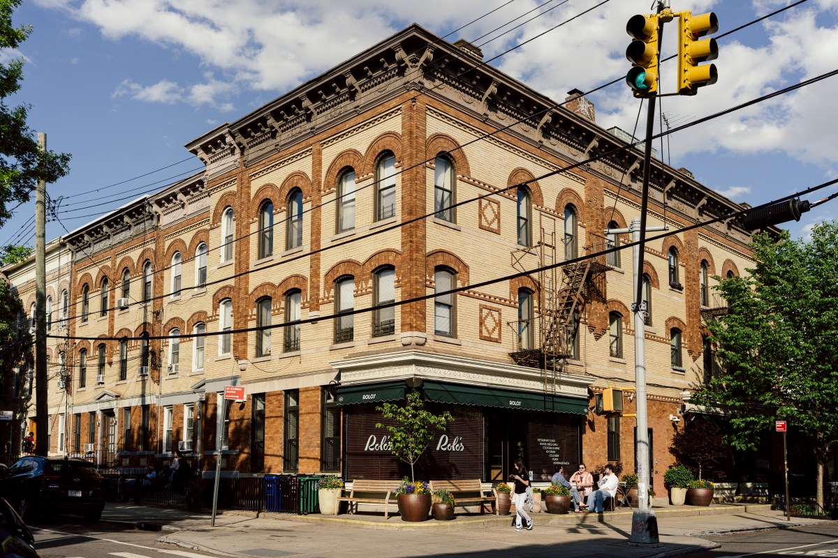 Exterior corner view of Rolo's restaurant in a historic brick building with green awning and outdoor seating
