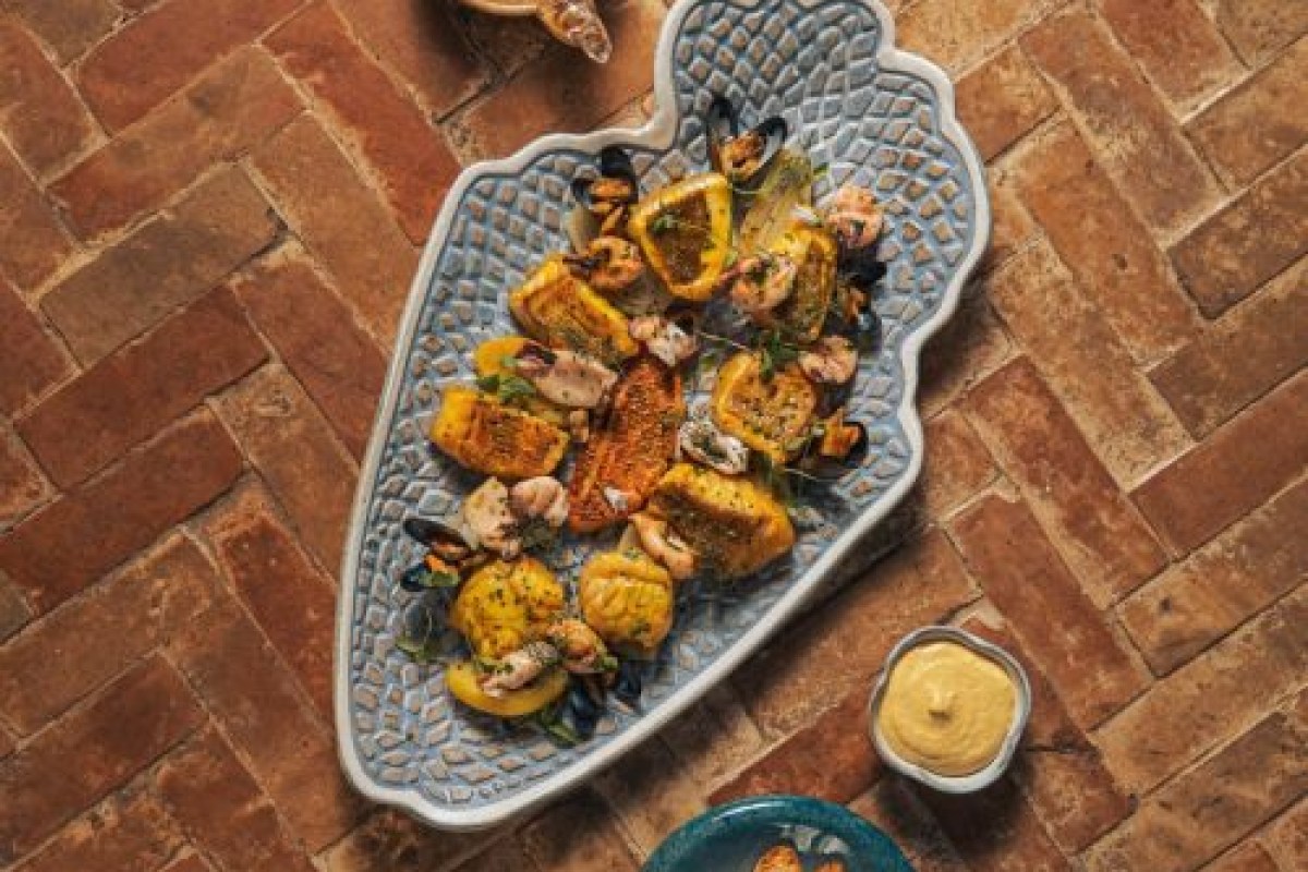 Overhead shot of a seafood platter with mussels, shrimp, and golden toasts on a decorative plate