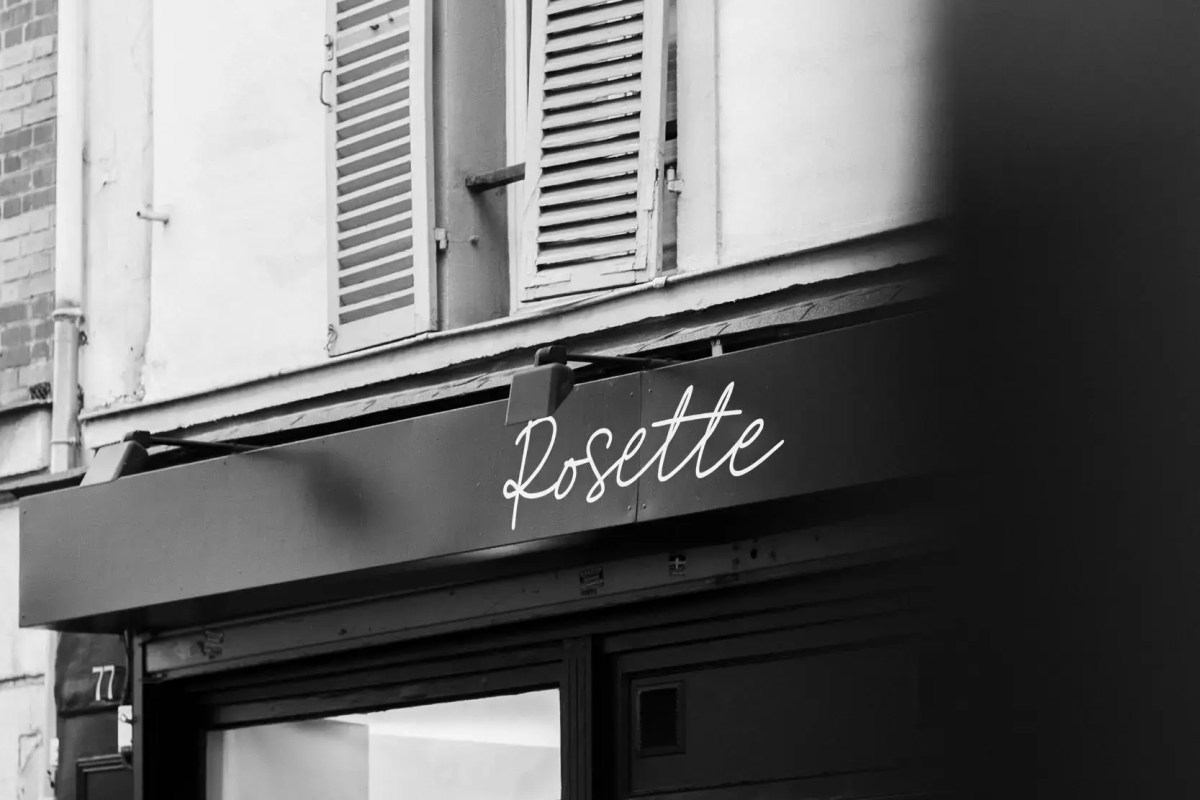 Black and white photo of Rosette restaurant's exterior storefront sign and shuttered windows above at number 77