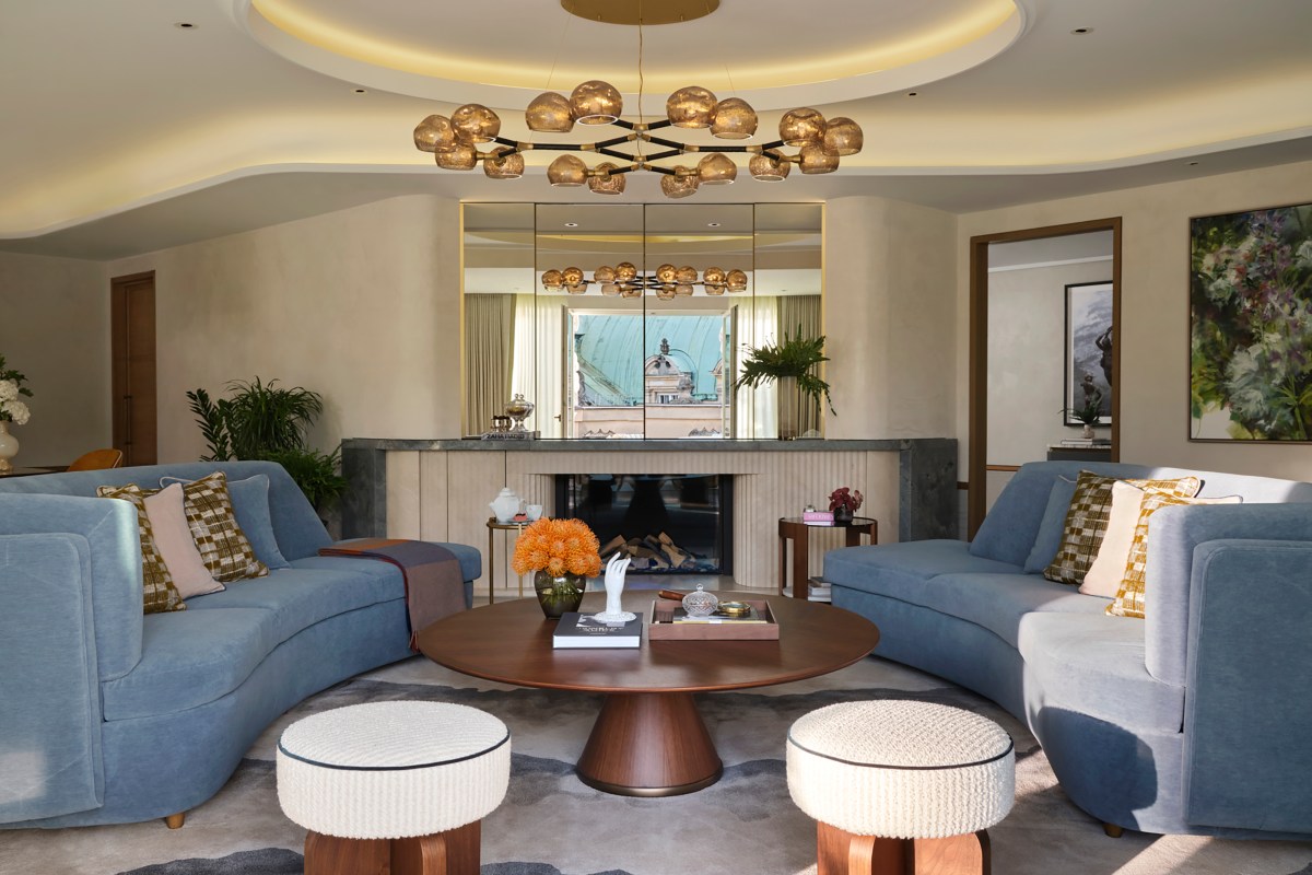 Hotel suite living room with blue sofas, round coffee table and fireplace