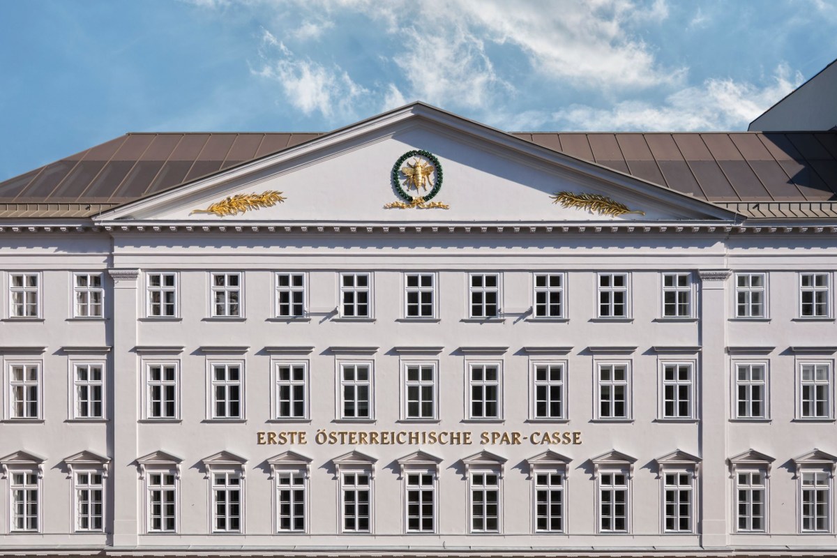 Full view of Rosewood Vienna's historic white façade with 'Erste Österreichische Spar-Casse' inscription and golden crest under a blue sky.