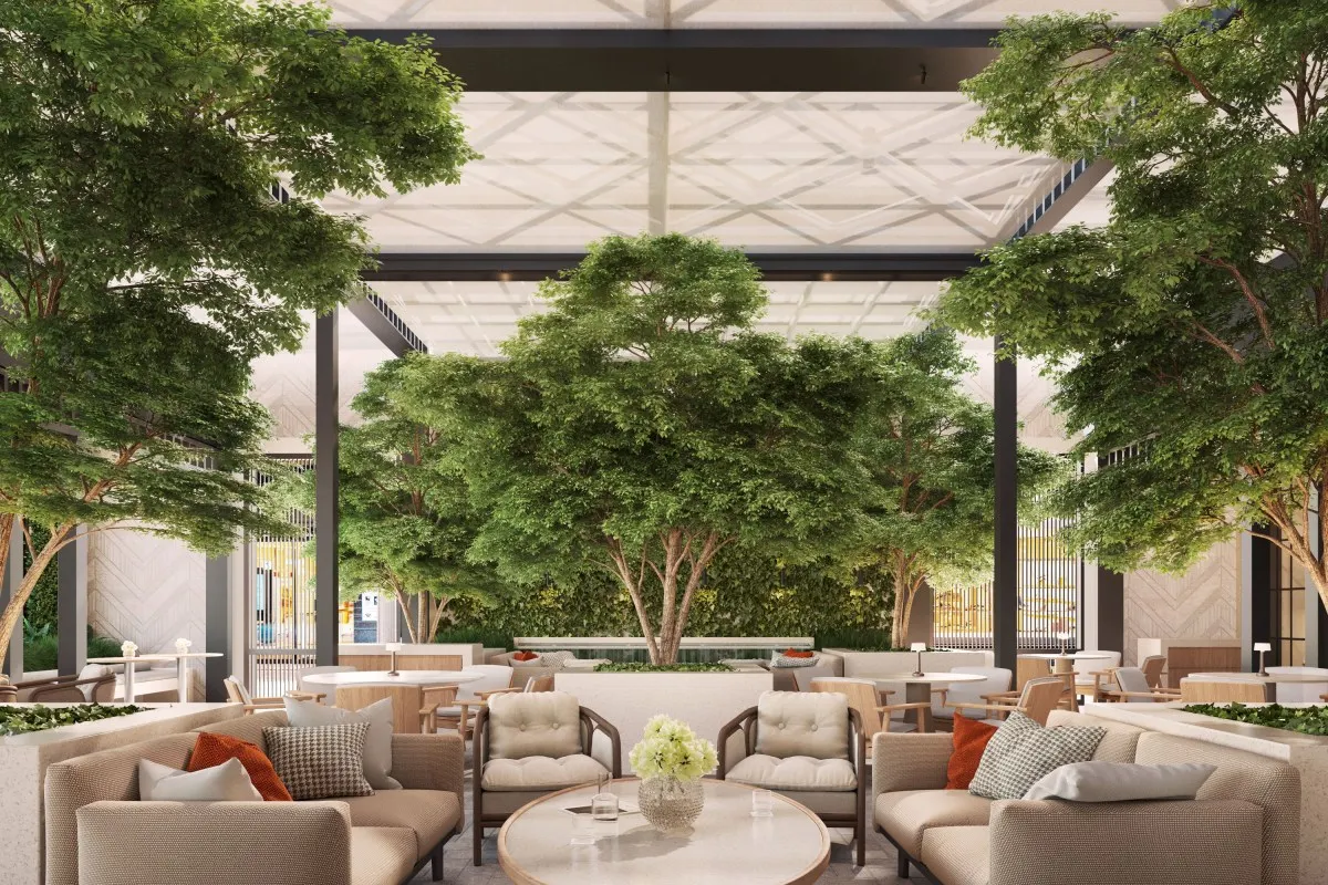 Indoor lounge area with comfortable seating under a skylight, centered around large potted trees