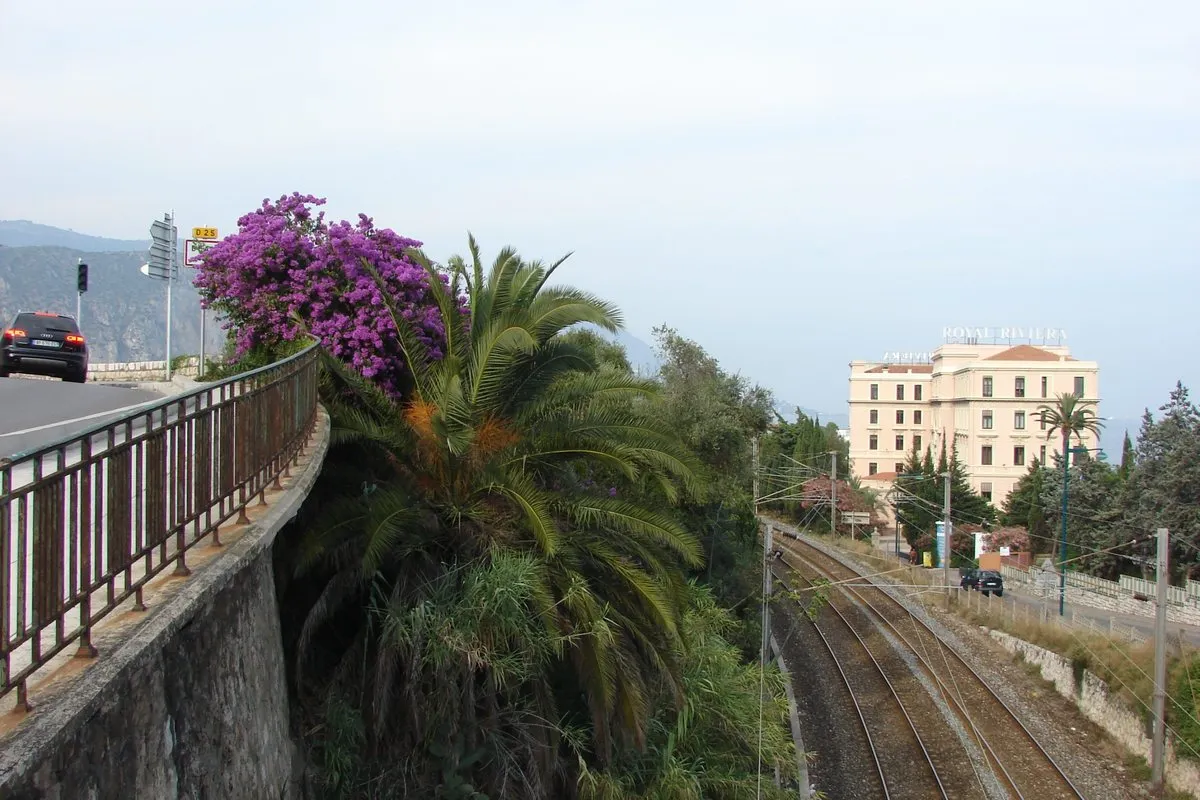 Royal-Riviera in Saint-Jean-Cap-Ferrat seen from the coast road with bougainvillea and palm trees in the foreground