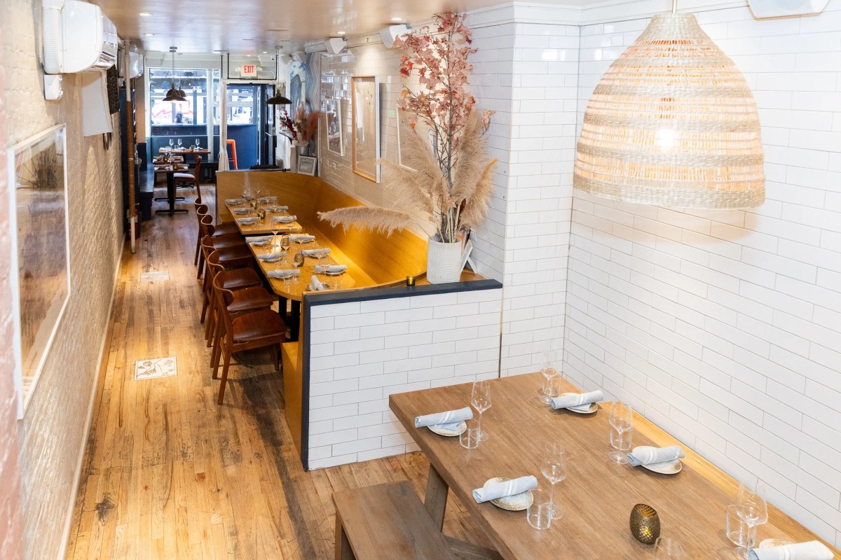 Narrow dining room with wooden tables, leather chairs, subway tile and hanging woven lamp