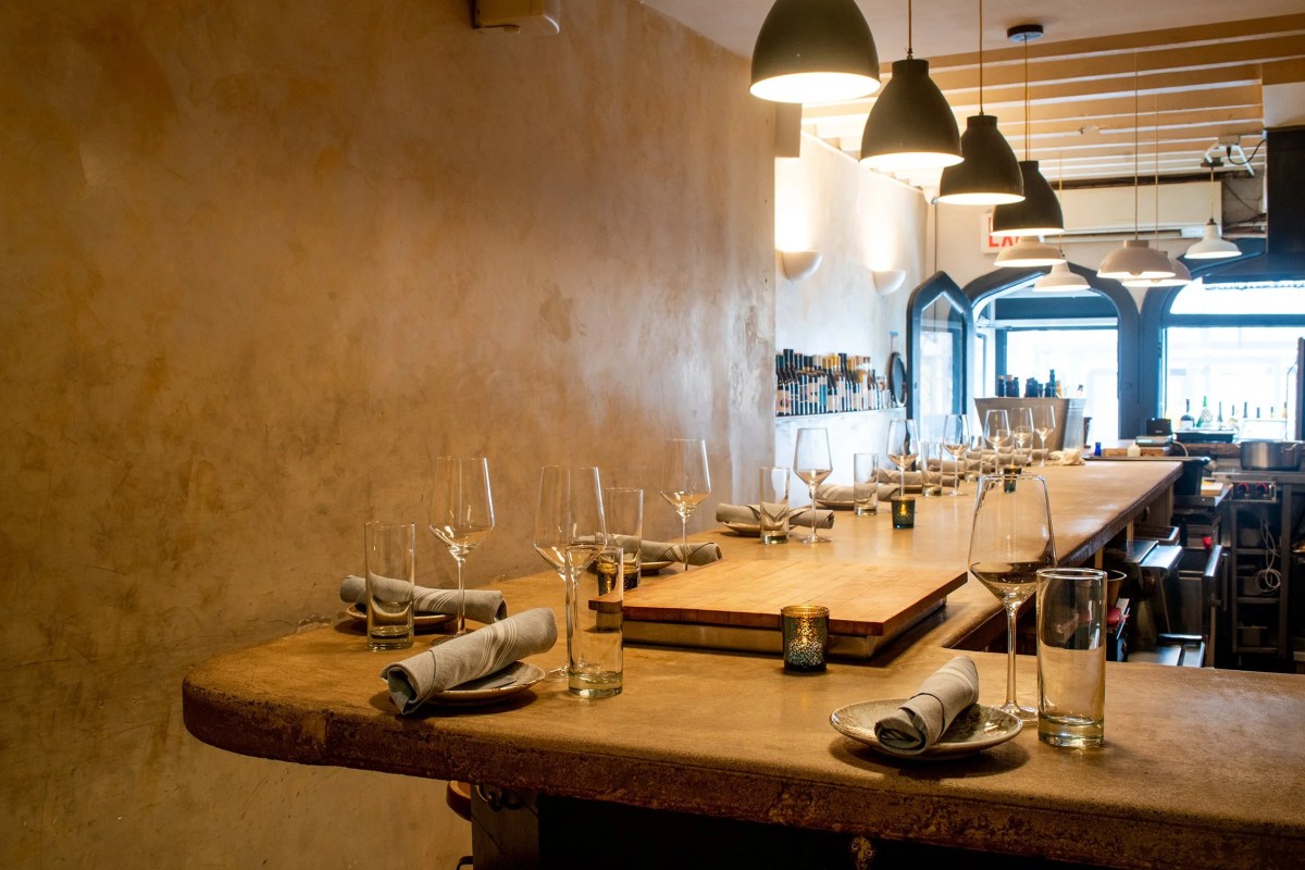 Restaurant bar counter set with wine glasses, napkins and pendant lighting