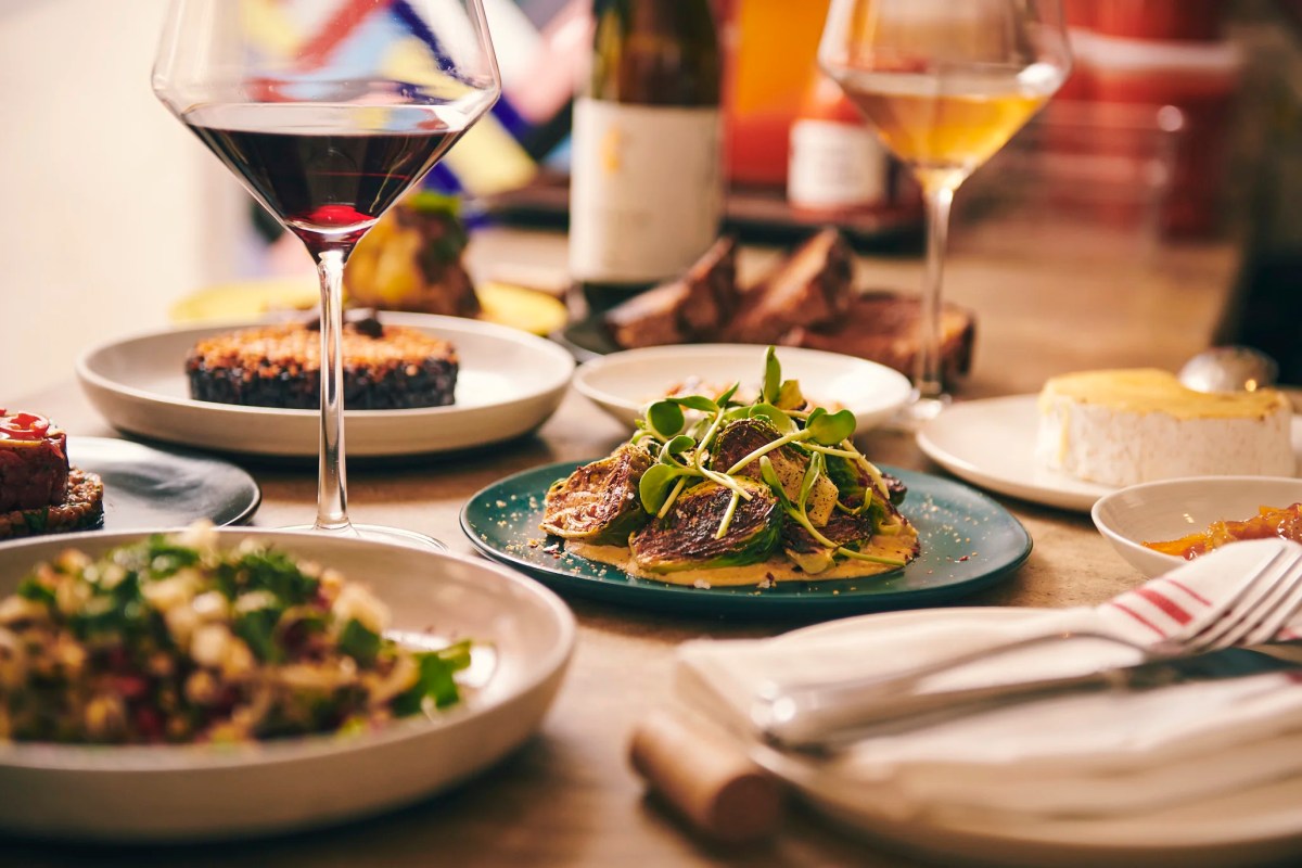 Table spread with multiple small plates, red and white wine glasses, and shared dishes