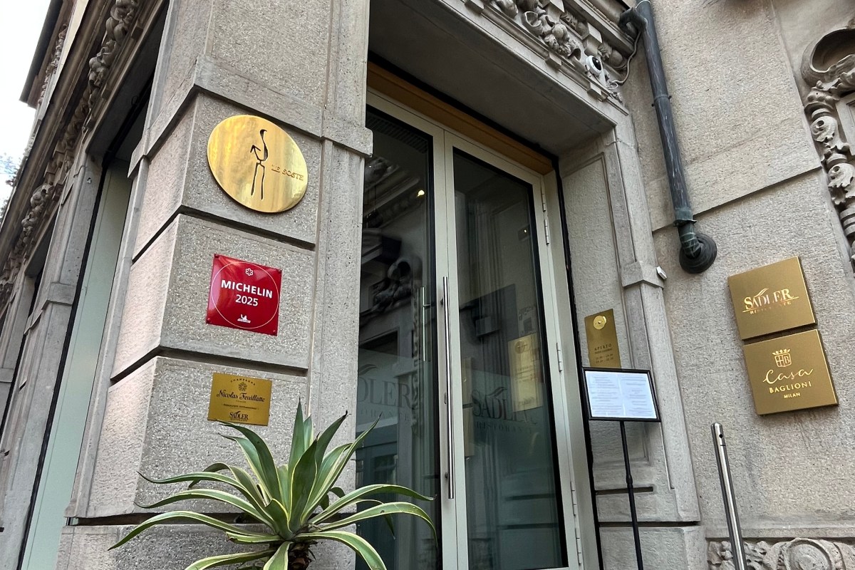 Entrance of Ristorante Sadler in Milan showing glass doors, stone facade, Michelin 2025 plaque and Sadler signage.