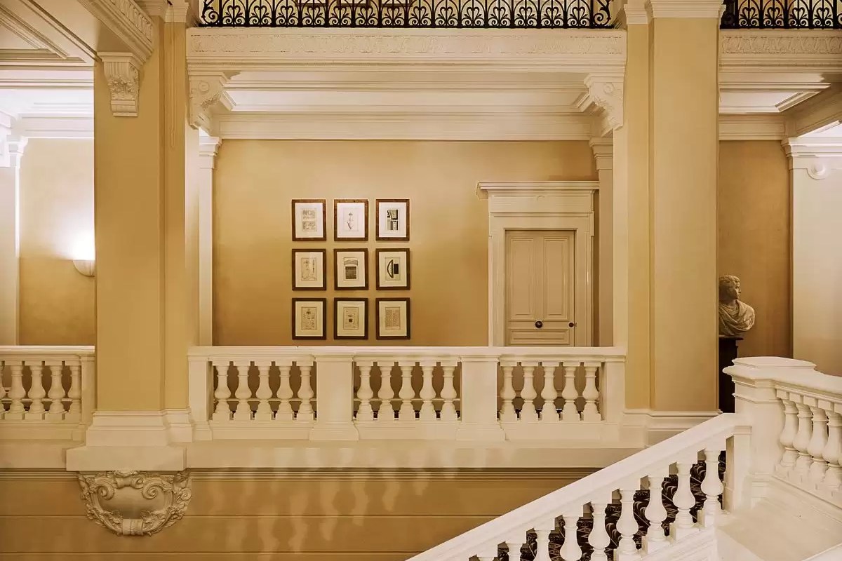 Grand hotel staircase landing with classical columns, balustrade and framed artwork
