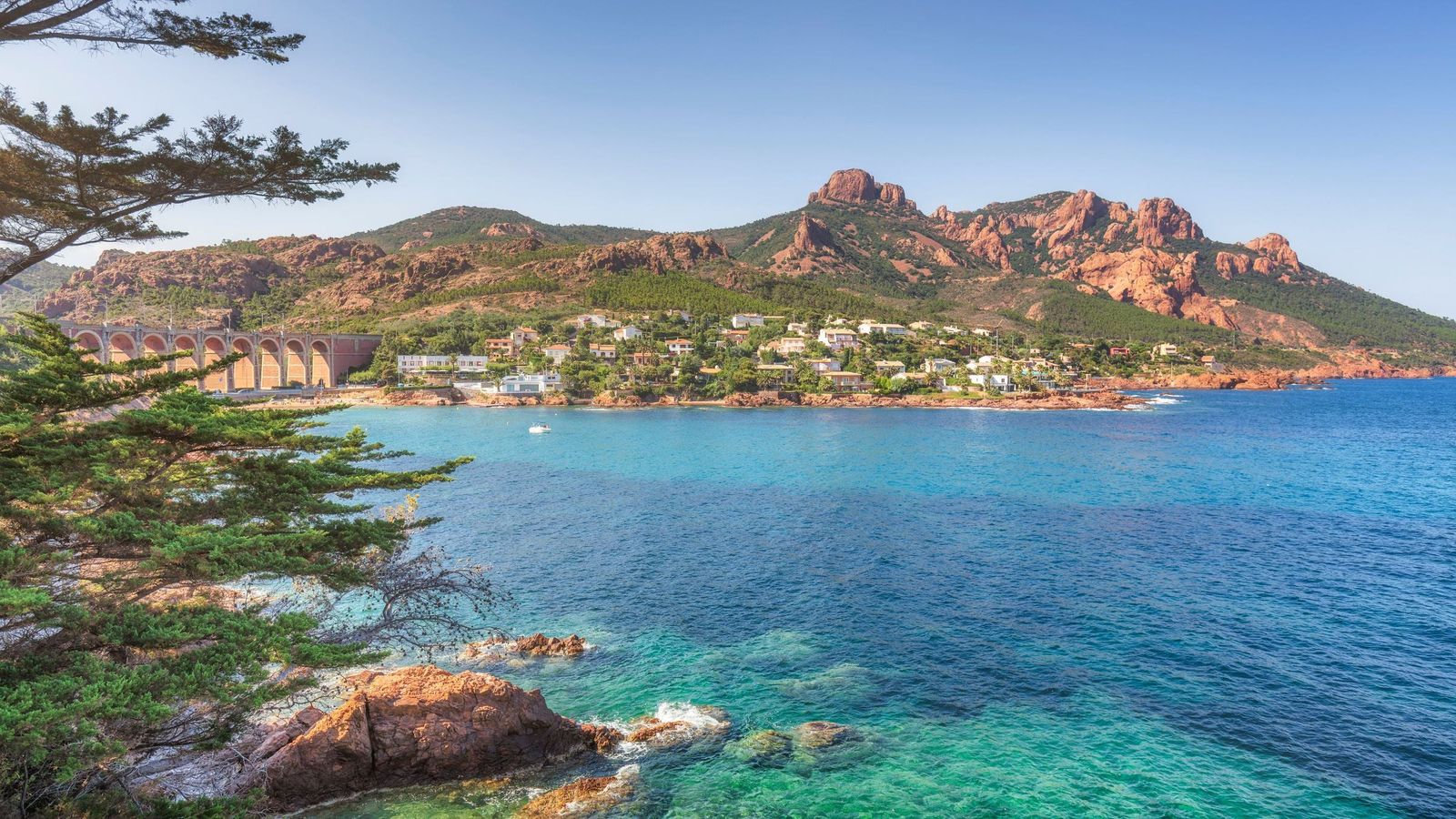 The red porphyry rocks of the Estérel above the turquoise bay of Anthéor, Saint-Raphaël, with the railway viaduct and villas along the shore