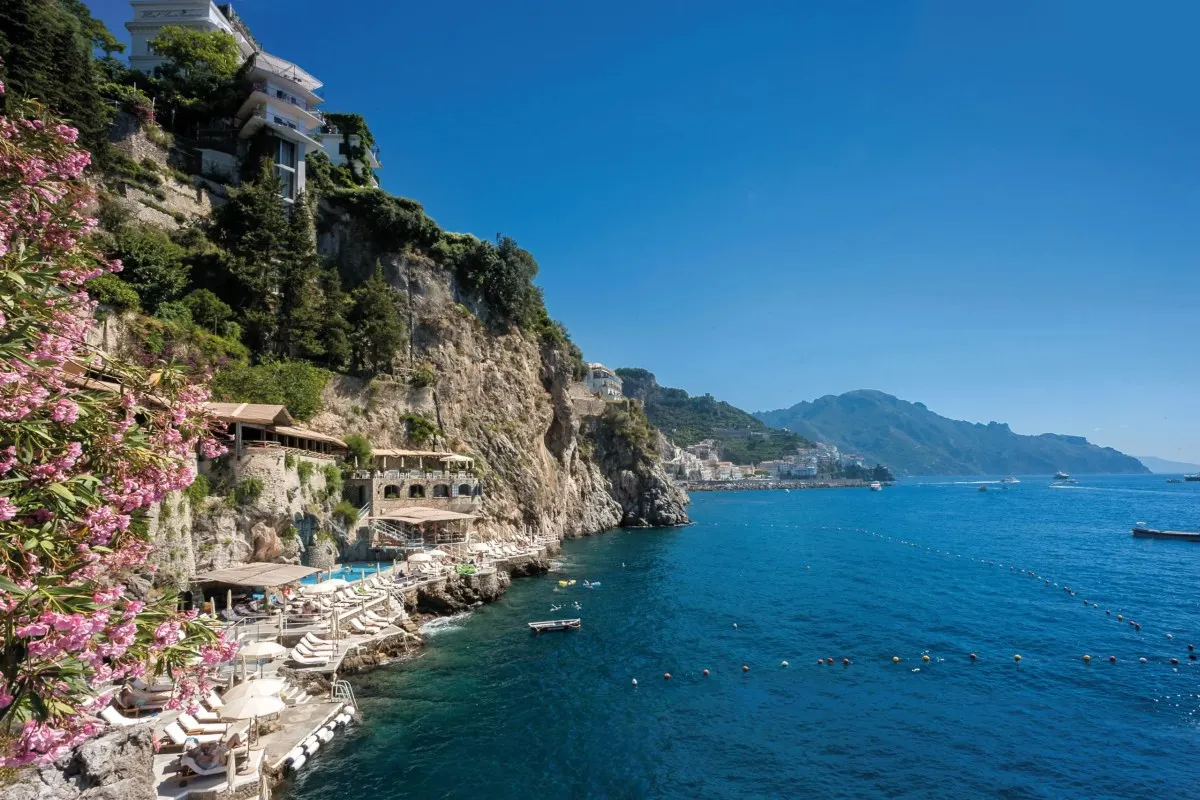 Santa Caterina hotel perched on cliffside above the sea along the Amalfi coast, with pink flowers in foreground