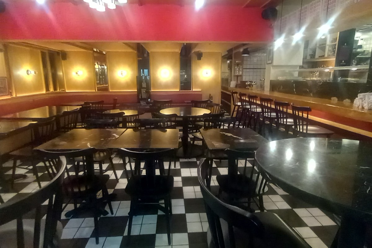 Interior dining room of See No Evil Pizza with checkerboard floor, dark tables, red walls, and bar seating