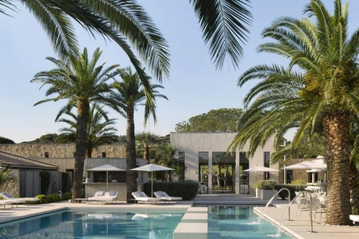 Pool with palm trees and hotel building facade in background