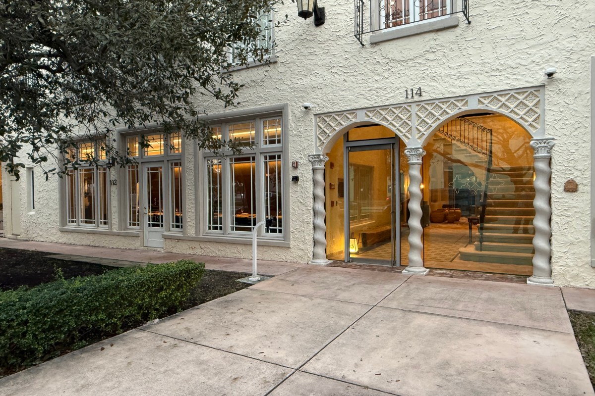 Exterior entrance of Shingo restaurant in Coral Gables, showing arched doorway, stucco facade, and warmly lit interior