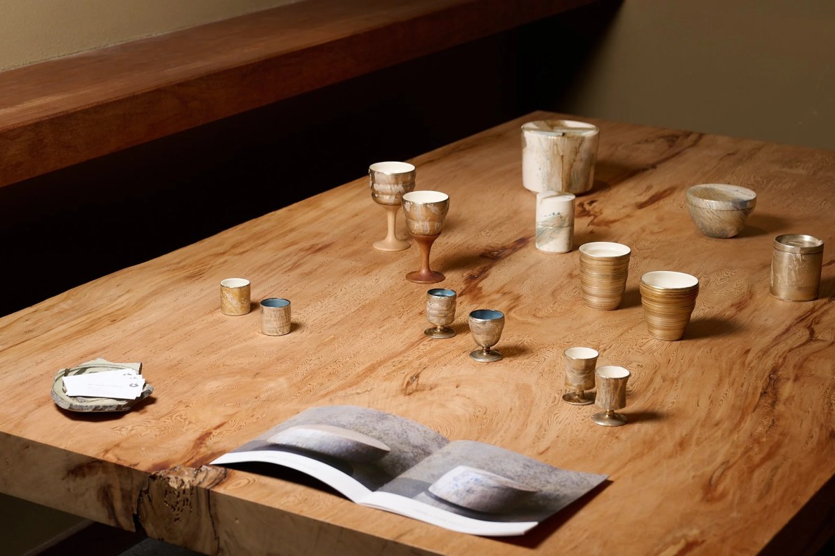 Live-edge wood table displaying an assortment of handmade ceramic cups, goblets, and tableware at Shingo