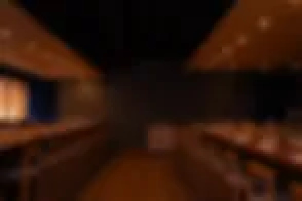 Blurry dim interior shot showing wooden beams or counter, possibly a dining area, too dark/blurry for quality use