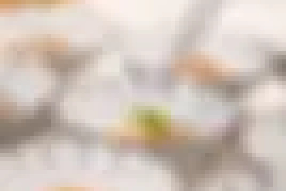 Blurry overhead shot of a table with plates and a lime or lemon slice, possibly a dish being served