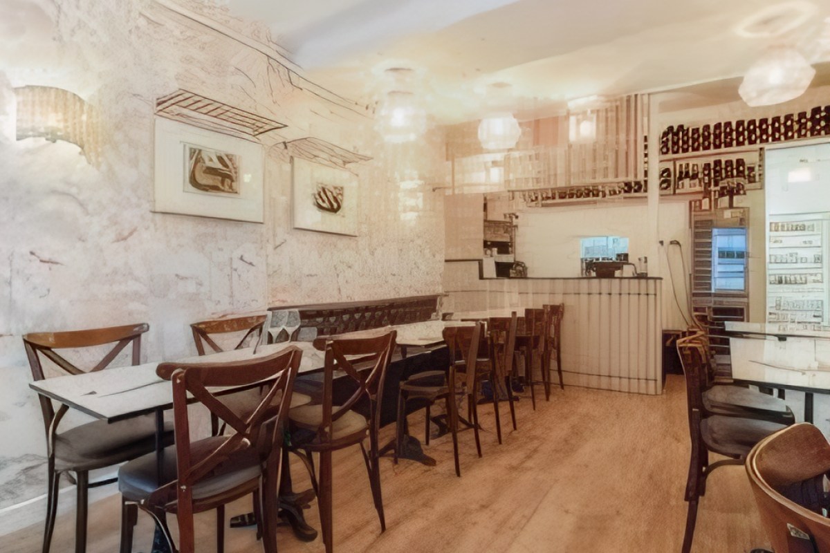 Interior dining room with wooden chairs, marble-top tables, wine bottle display and bar area