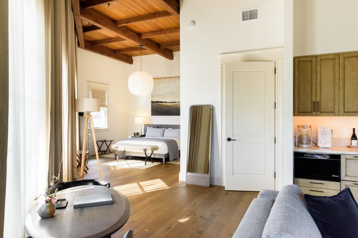 Guest suite with wood-beamed ceiling, bed, kitchenette, and sitting area