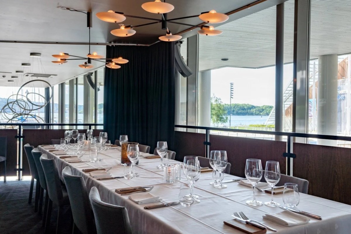 Private dining room with long table set for a group, overlooking the harbor through large windows