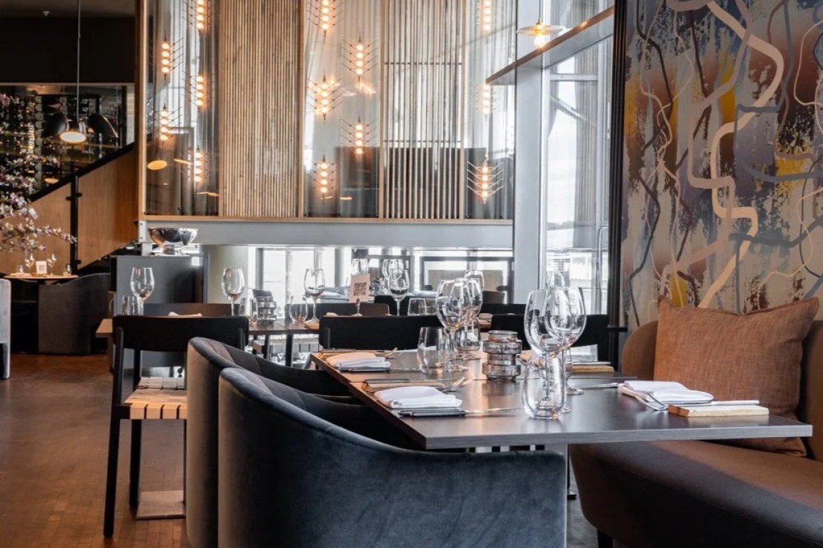Modern restaurant dining room with set tables, wine glass glasses and ambient lighting