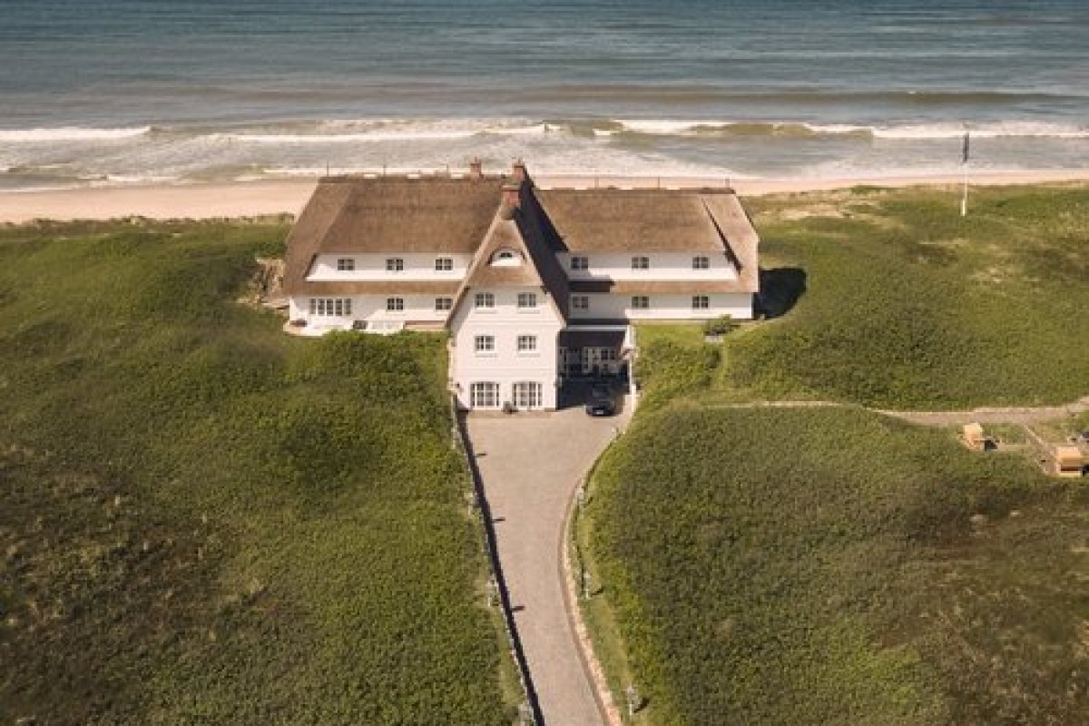Aerial view of the thatched-roof hotel perched on dunes directly facing the sea and beach