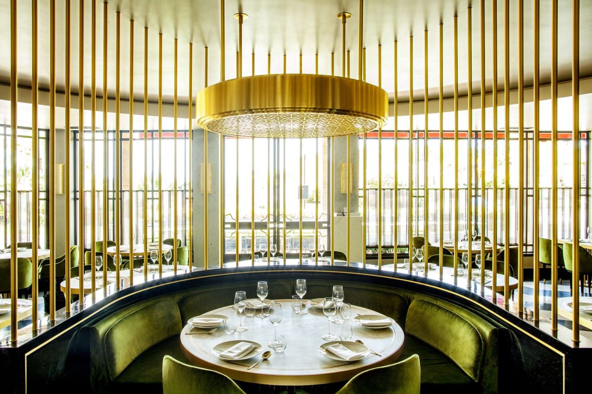 Elegant dining room with gold vertical bar dividers, round booth table set with glassware, large windows