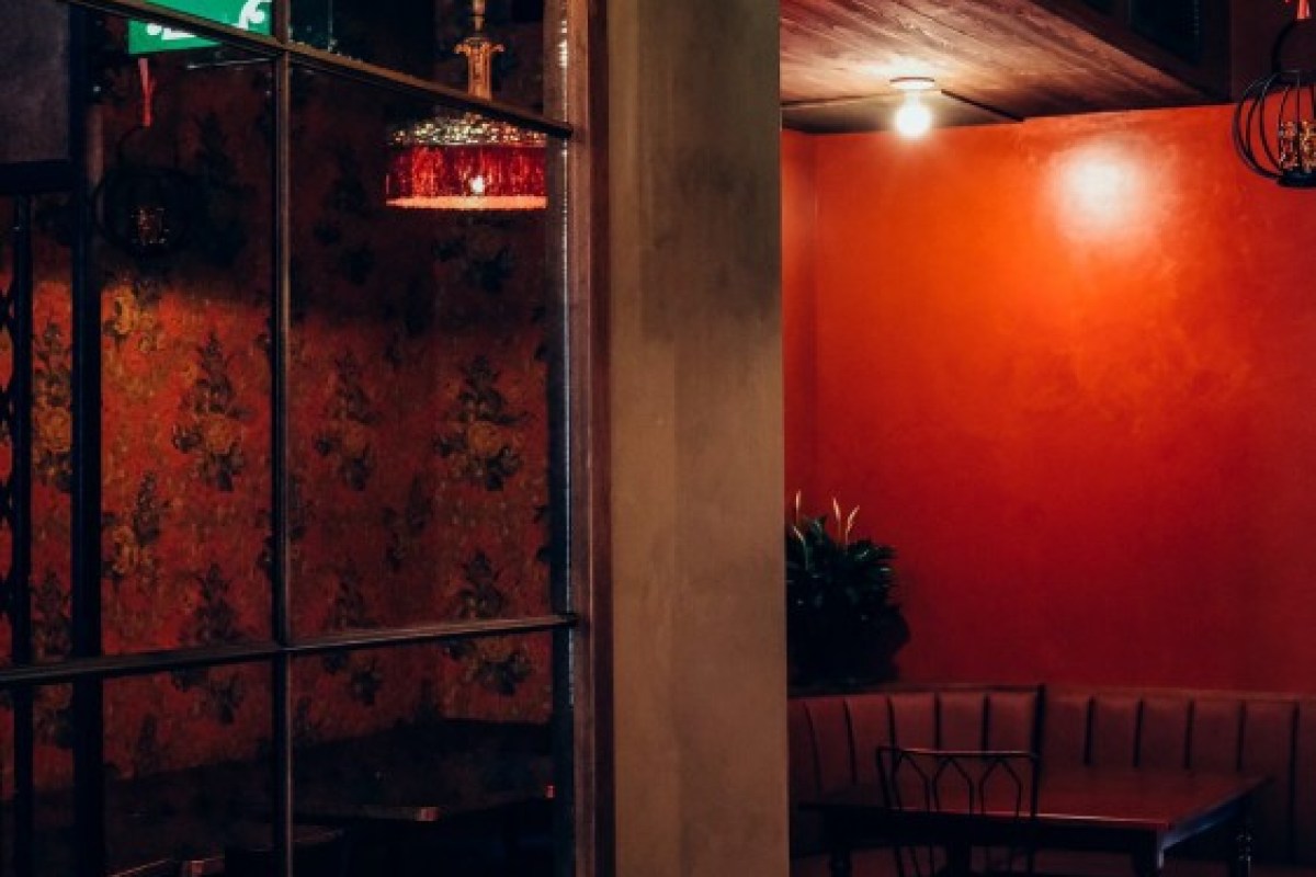 Interior dining area with red walls, mirrored panel, and booth seating at Soothr restaurant