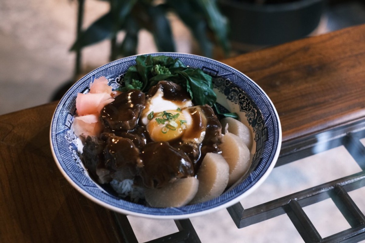 Blue and white patterned bowl with rice, braised meat, soft egg, radish, and greens