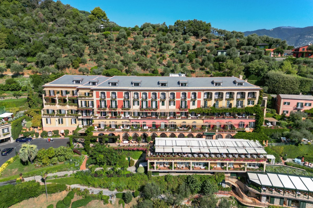Aerial daytime view of Splendido Hotel's ochre and pink façade amid green hillside, Portofino.