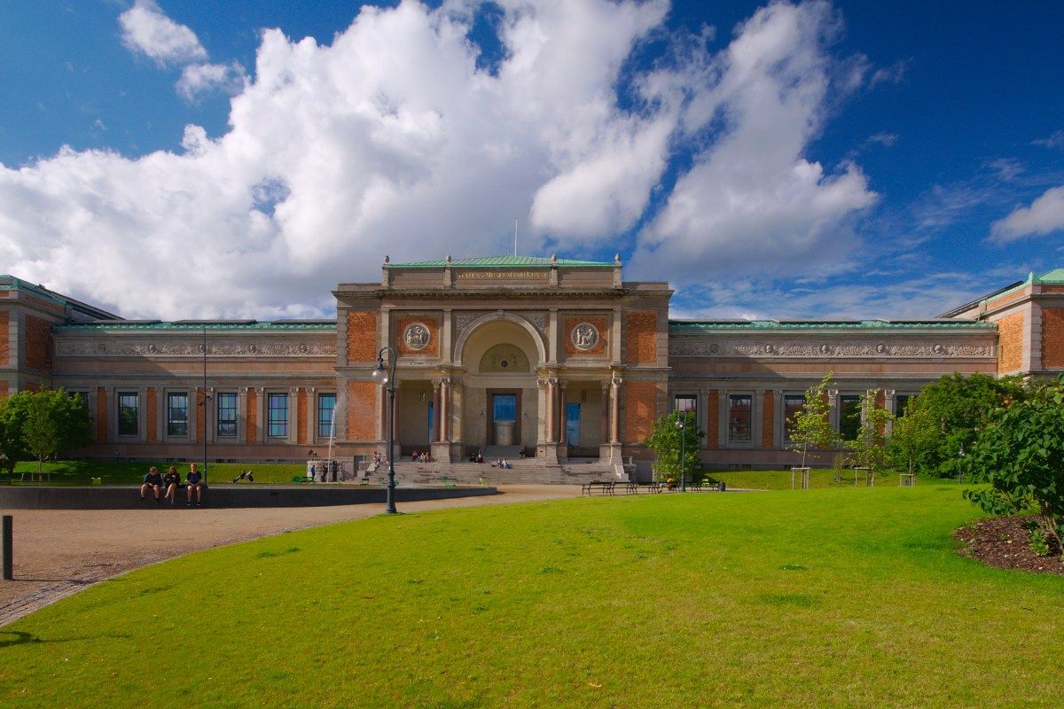 Exterior front facade of Statens Museum for Kunst with lawn, under blue sky with clouds