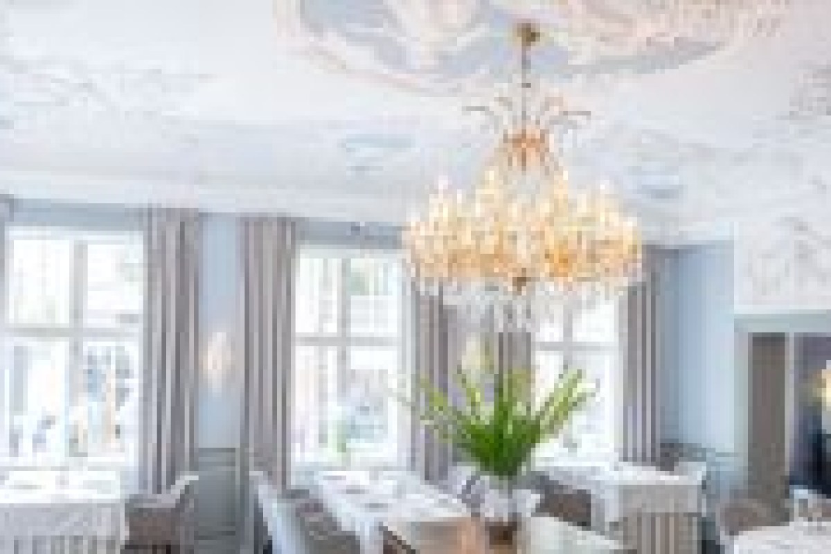 Dining room view with chandelier, large windows, grey curtains and set tables