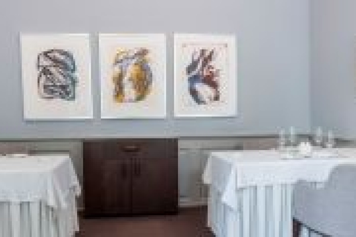 Dining room wall with three framed artworks above set tables