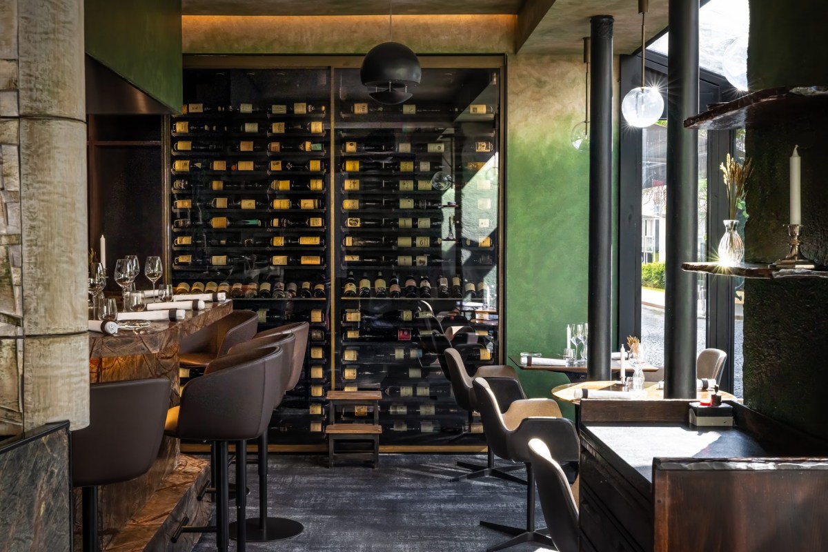 Interior dining room with wine wall, bar seating, and green walls at Substance restaurant