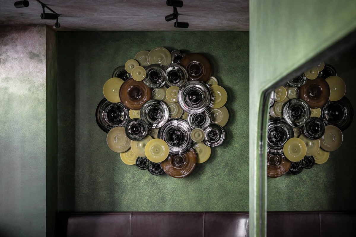 Close-up of decorative glass disc wall art on green wall in the dining room