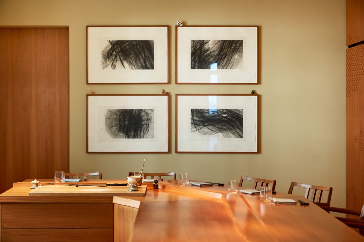 Dining room with wooden sushi counter, chairs, place settings and framed abstract art on wall