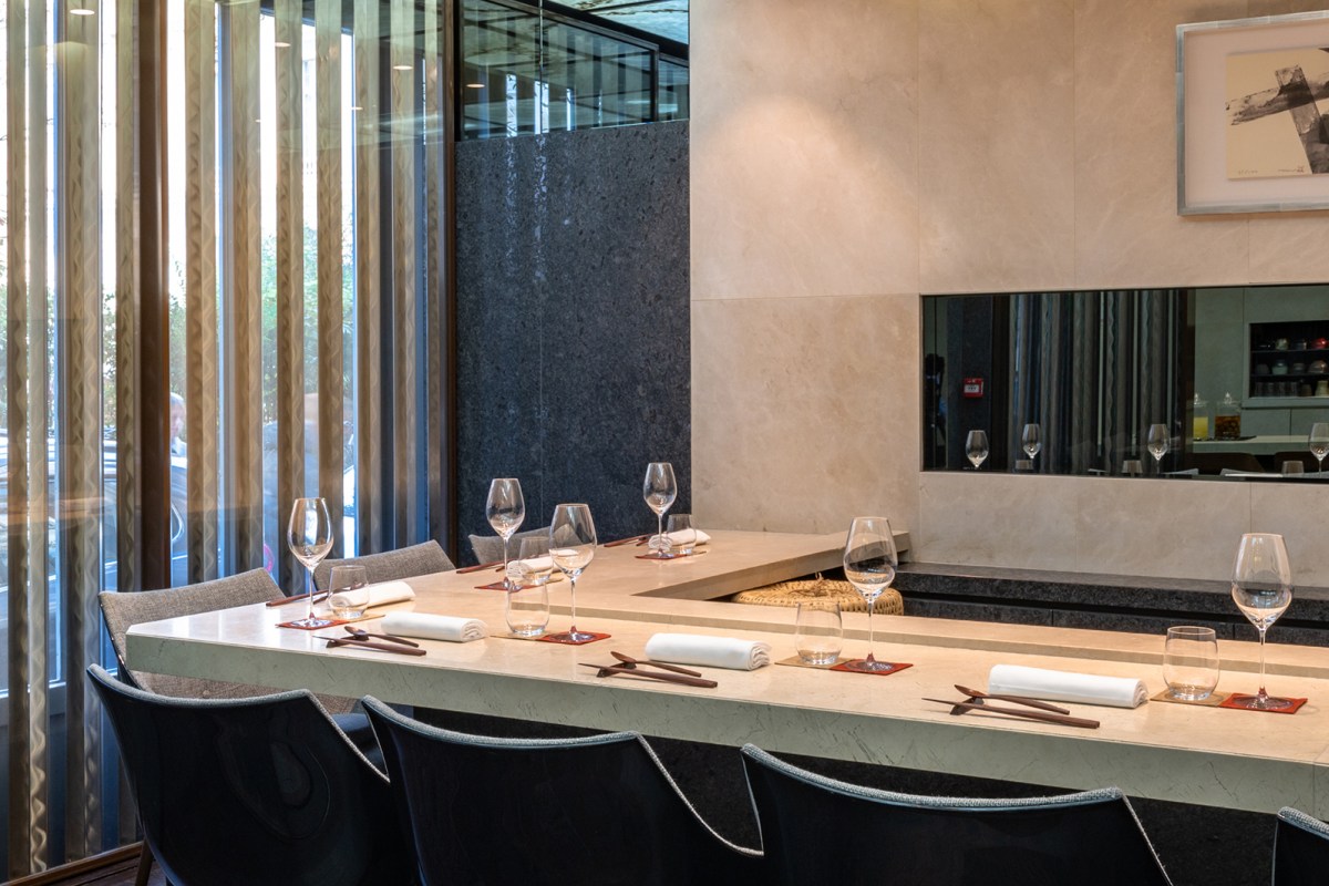 Dining counter with place settings, wine glasses, chopsticks, and large windows letting in natural light