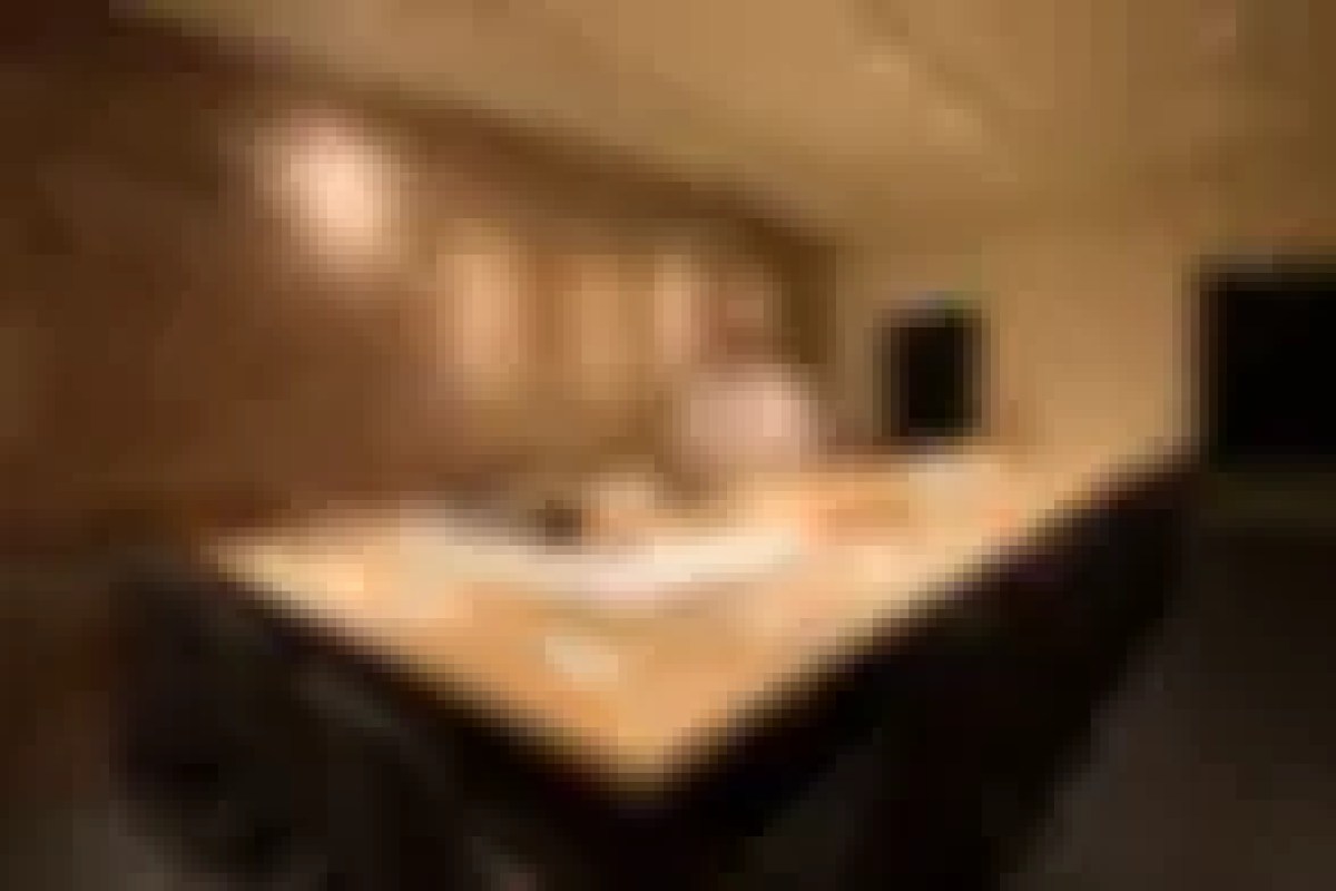 Blurry view of a wooden sushi counter in a dimly lit dining room