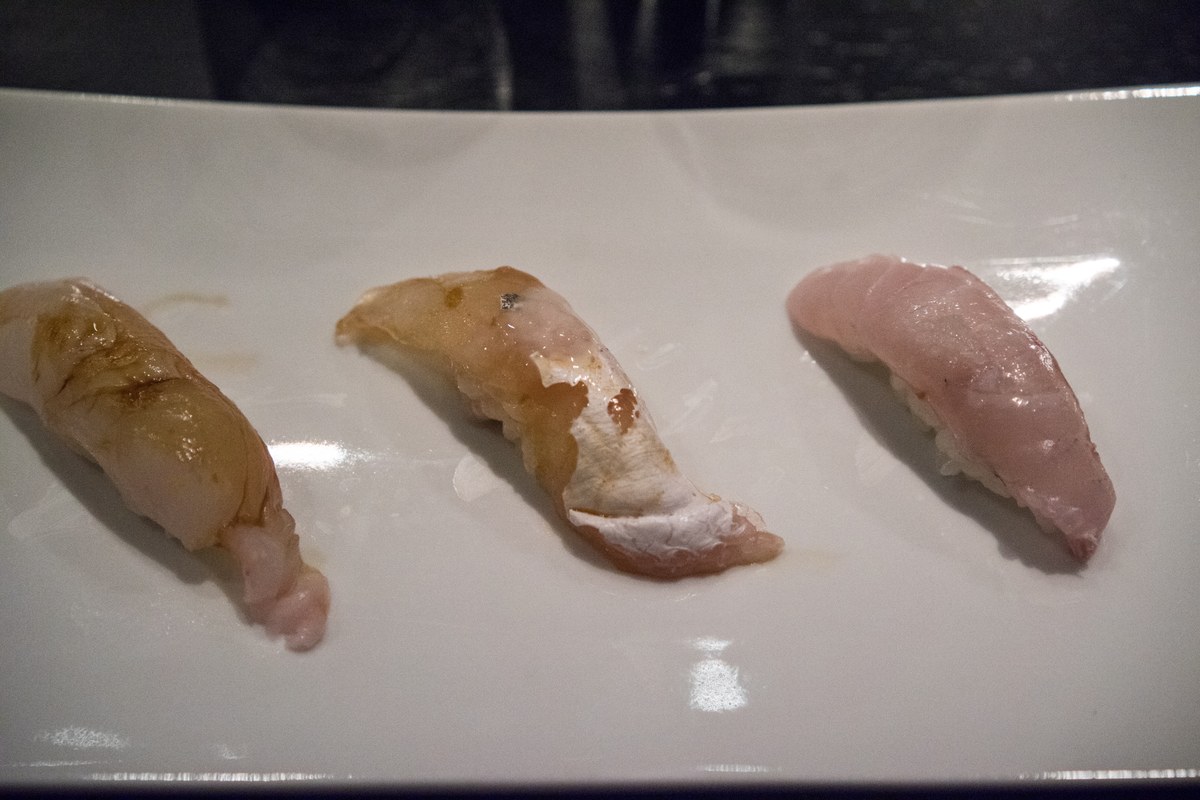 Three pieces of nigiri sushi arranged on a white rectangular plate